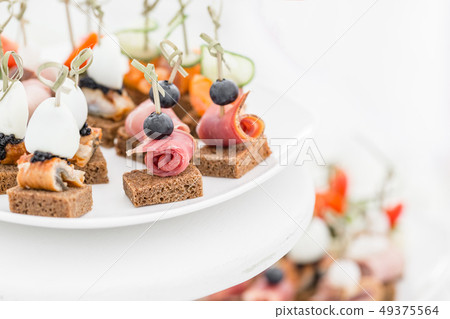 Buffet table. Assortment of canapes. Banquet service in restaurant. Catering food, snacks on white Buffet table. Assortment of canapes. Banquet service in restaurant. Catering food, snacks on white 49375564