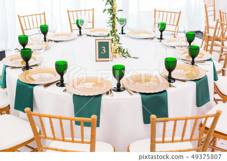 Interior of tent for wedding dinner, ready for guests. Served round banquet table. Golden dishes Interior of tent for wedding dinner, ready for guests. Served round banquet table. Golden dishes 49375807