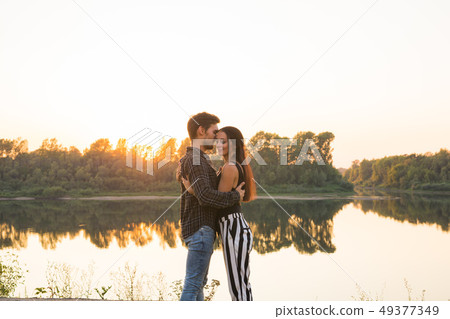 Romantic and people concept - young couple hugging together near the river or lake and enjoying Romantic and people concept - young couple hugging together near the river or lake and enjoying 49377349