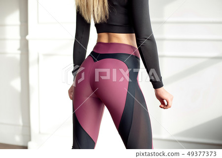 Young slim woman with an athletic body long blonde hair wearing in black sports sportswear top and Young slim woman with an athletic body long blonde hair wearing in black sports sportswear top and 49377373