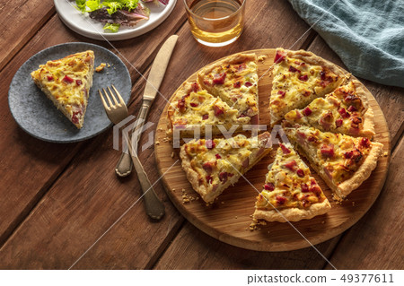 A photo of a quiche with wine and salad on a dark rustic wooden background with a place for text 49377611