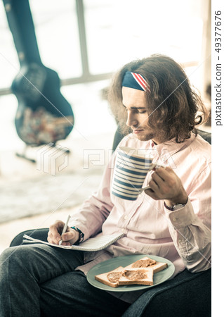 Focused dark-haired musician having peanut butter sandwiches 49377676