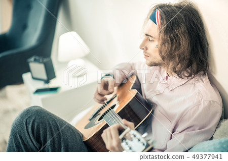 Emotional long-haired artist being concentrated on personal musical instrument 49377941
