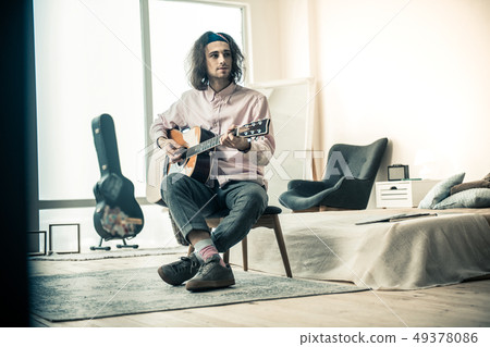 Pleasant dark-haired young musician practicing in guitar mastery 49378086