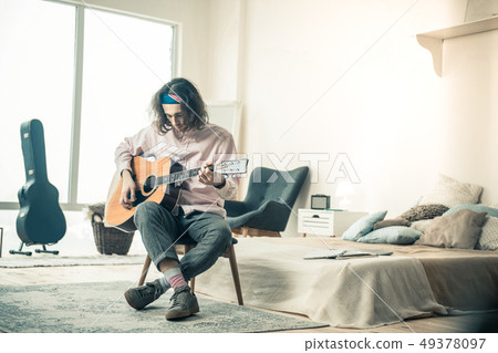 Dark-haired focused man in light shirt sitting with crossed legs 49378097