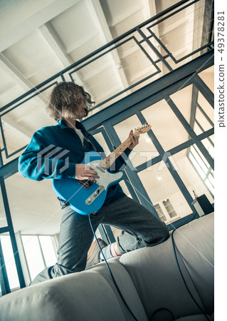 Posing good-looking guy with wavy haircut professionally playing on guitar