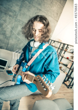 Careless long-haired man being inspired while playing music 49378663