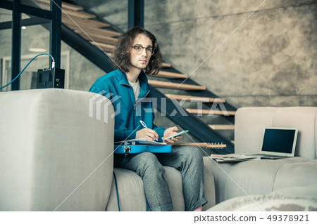 Serious inspired guy in clear glasses being involved in creation process 49378921