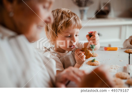 A senior grandmother with small toddler boy making cakes at home. 49379187