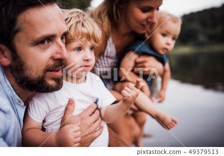 A young family with two toddler children outdoors by the river in summer. A young family with two toddler children outdoors by the river in summer. 49379513