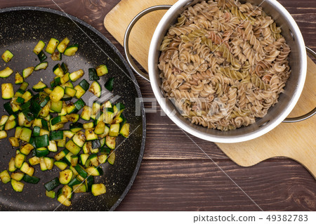 Fusilli pasta with zucchini on brown wood Fusilli pasta with zucchini on brown wood 49382783