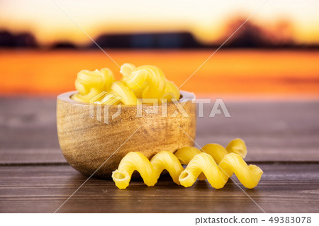 Cavatappi pasta raw with autumn field behind 49383078
