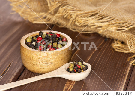 Four colors of peppercorns on brown wood Four colors of peppercorns on brown wood 49383317