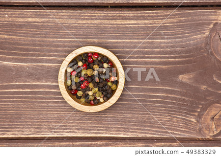 Four colors of peppercorns on brown wood Four colors of peppercorns on brown wood 49383329