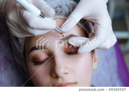 Permanent Makeup For Eyebrows. Microblading brow. Beautician Doing Eyebrow Tattooing For Female Face 49384597