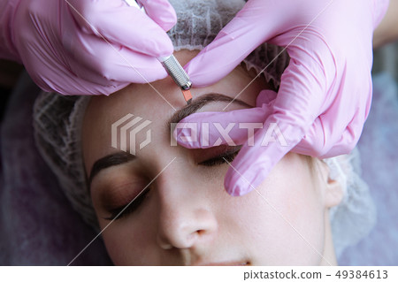 Permanent Makeup For Eyebrows. Microblading brow. Beautician Doing Eyebrow Tattooing For Female Face Permanent Makeup For Eyebrows. Microblading brow. Beautician Doing Eyebrow Tattooing For Female Face 49384613