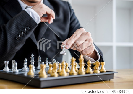 Hands of confident businessman playing chess game 49384904