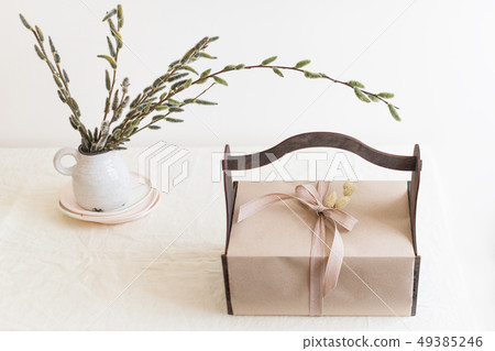 Gift box with spring flowers on light natural fabric background. Easter basket with presents 49385246