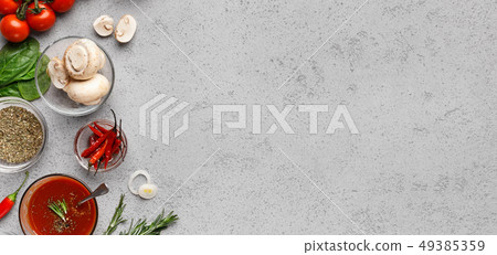 Pizza ingredients, vegetables and herbs on grey table Pizza ingredients, vegetables and herbs on grey table 49385359