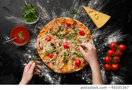 Chef decorating pizza with rocket salad and cherry tomatoes Chef decorating pizza with rocket salad and cherry tomatoes 49385367