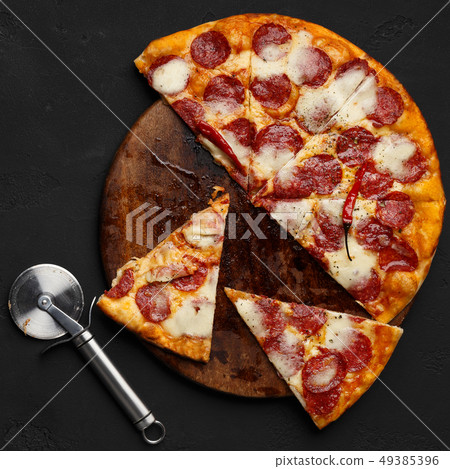 Cutted pepperoni pizza on cutting board with cutter nearby Cutted pepperoni pizza on cutting board with cutter nearby 49385396