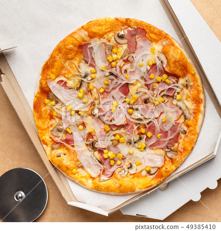 Cardboard box with pizza and cutter on wooden background Cardboard box with pizza and cutter on wooden background 49385410