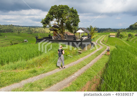 Female tourist walking a path among Jatiluwih rice terraces and plantation in Bali, Indonesia. Female tourist walking a path among Jatiluwih rice terraces and plantation in Bali, Indonesia. 49389037