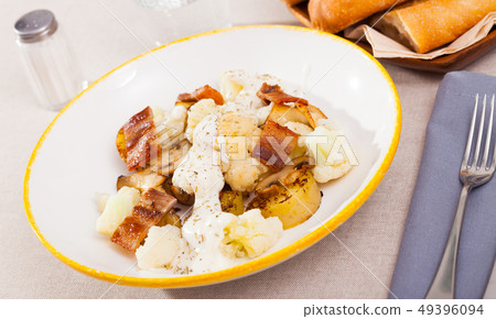 Baked potatoes with cauliflower, bacon, cheese sauce 49396094