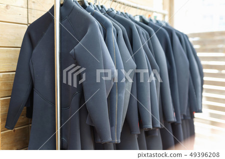 Black surfing wetsuits hanging on rack for rent in surf club 49396208