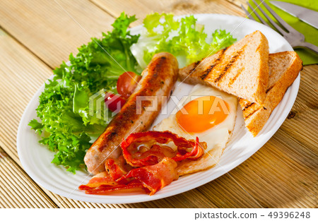 Fried eggs with bacon, sausage, bread 49396248
