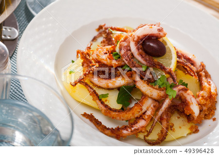 Delicious cooked squid or octopus tentacles with lemon and parsley on a plate Delicious cooked squid or octopus tentacles with lemon and parsley on a plate 49396428