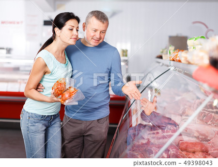 Positive couple customers choosing meat in shop Positive couple customers choosing meat in shop 49398043