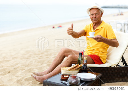 Glad man sitting with cup and giving thumbs up 49398061