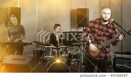 Guy guitar player and singer practicing with band members in re 49398497