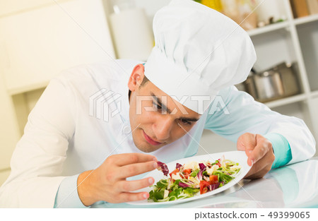 Young man is evaluating prepared dish Young man is evaluating prepared dish 49399065