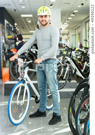 Man in helmet standing with sport bicycle in bicycle store Man in helmet standing with sport bicycle in bicycle store 49399122