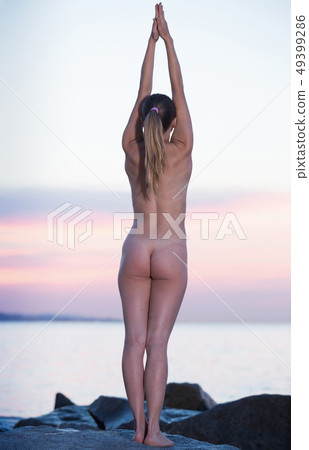 Young naked female practising yoga poses at seaside Young naked female practising yoga poses at seaside 49399286