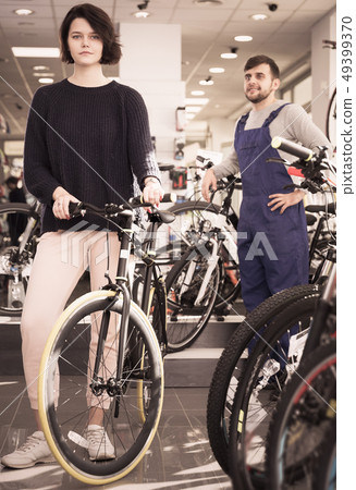 man seller and woman standing in bicycle store man seller and woman standing in bicycle store 49399370