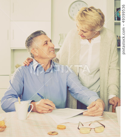 Mature married couple discuss contract and sign important documents Mature married couple discuss contract and sign important documents 49399536