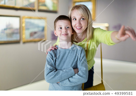 Mother and son regarding paintings in halls of museum 49399581