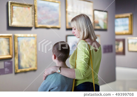 Mother and son regarding paintings in halls of museum 49399708
