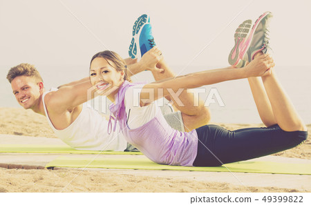 Guy and woman doing workout on beach by ocean Guy and woman doing workout on beach by ocean 49399822