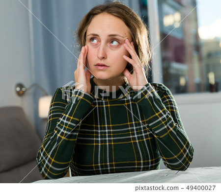 Portrait of sorrowful woman sitting at home Portrait of sorrowful woman sitting at home 49400027
