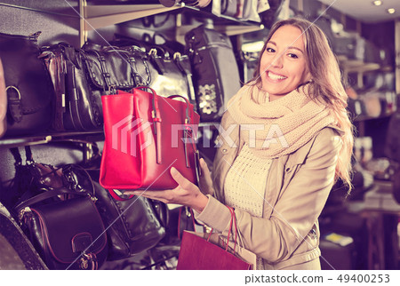friendly woman buying leather purse in shop 49400253
