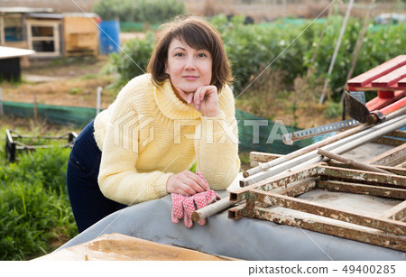 Girl in a yellow sweater works in the garden of a country house 49400285