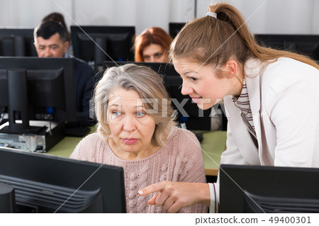 Young female teacher explaining computer skills to mature woman Young female teacher explaining computer skills to mature woman 49400301