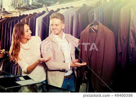Laughing couple examining various suits Laughing couple examining various suits 49400386