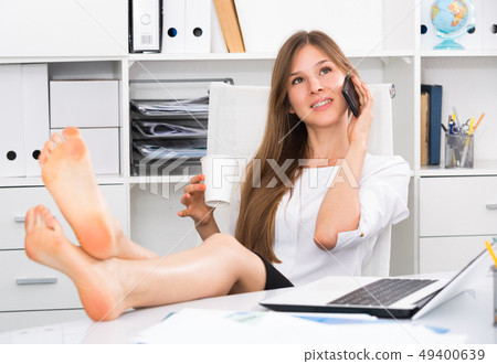 Female with bare feet on desk talking on phone Female with bare feet on desk talking on phone 49400639