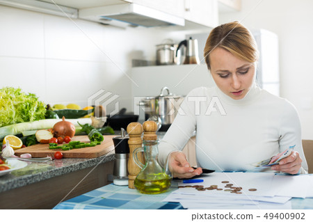 Broke woman with money and bills in kitchen Broke woman with money and bills in kitchen 49400902