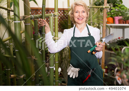 Mature female florist standing amongst plants 49401074